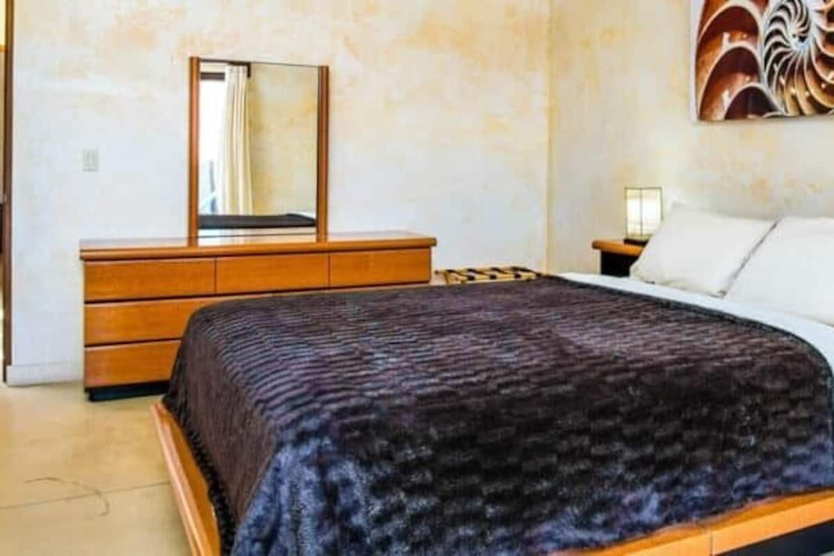 Un dormitorio con cama, cómoda, mesita de noche y un cuadro en la pared.