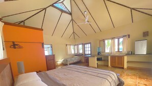 Un dormitorio con cama, escritorio, silla, dispensador de agua y refrigerador.