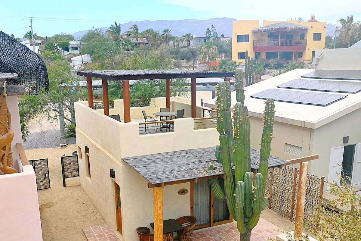 Una casa moderna con un patio, un cactus y vistas a las montañas.