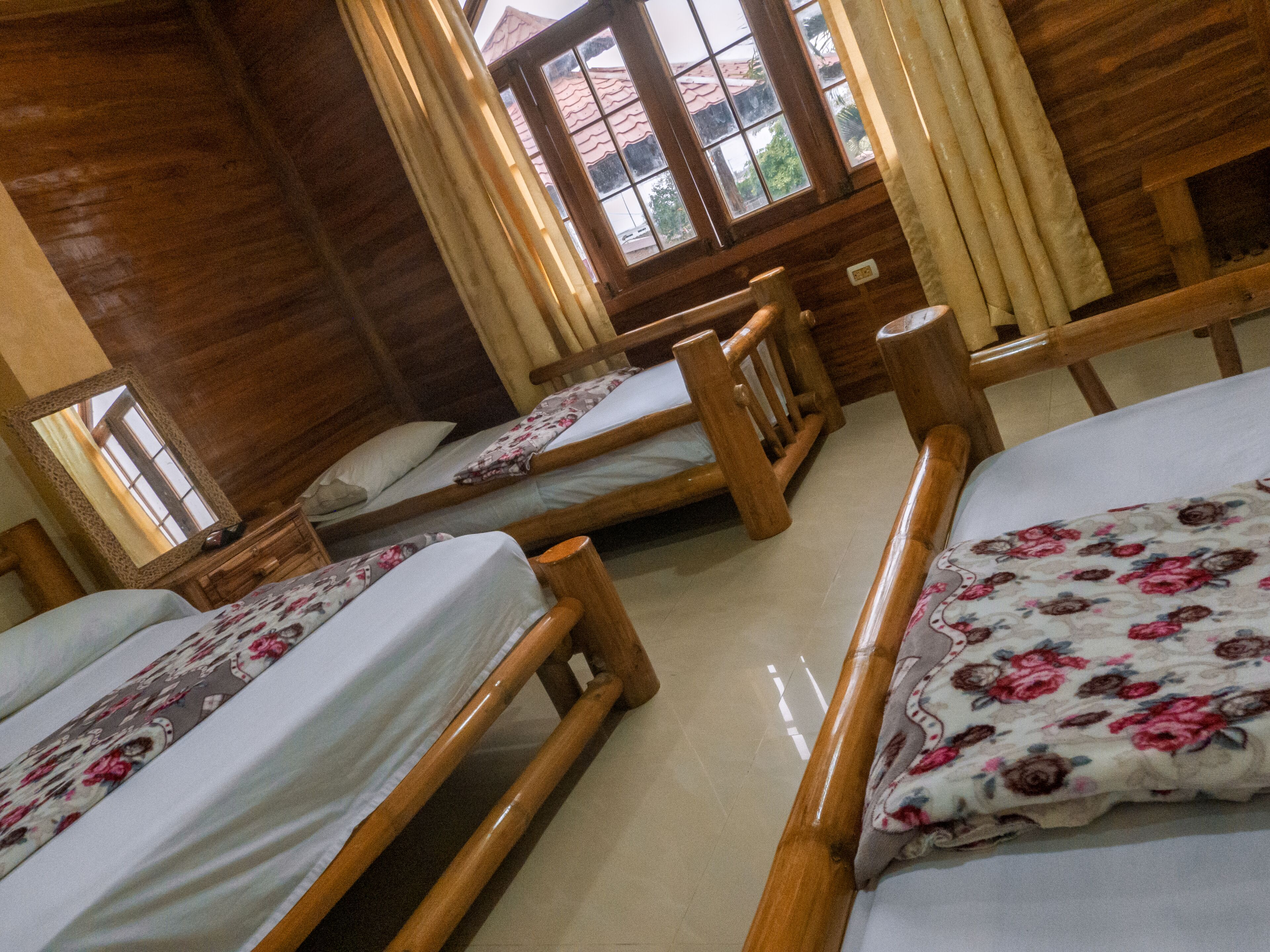 A wooden cabin-style room with three wooden beds, each with a floral bedspread.