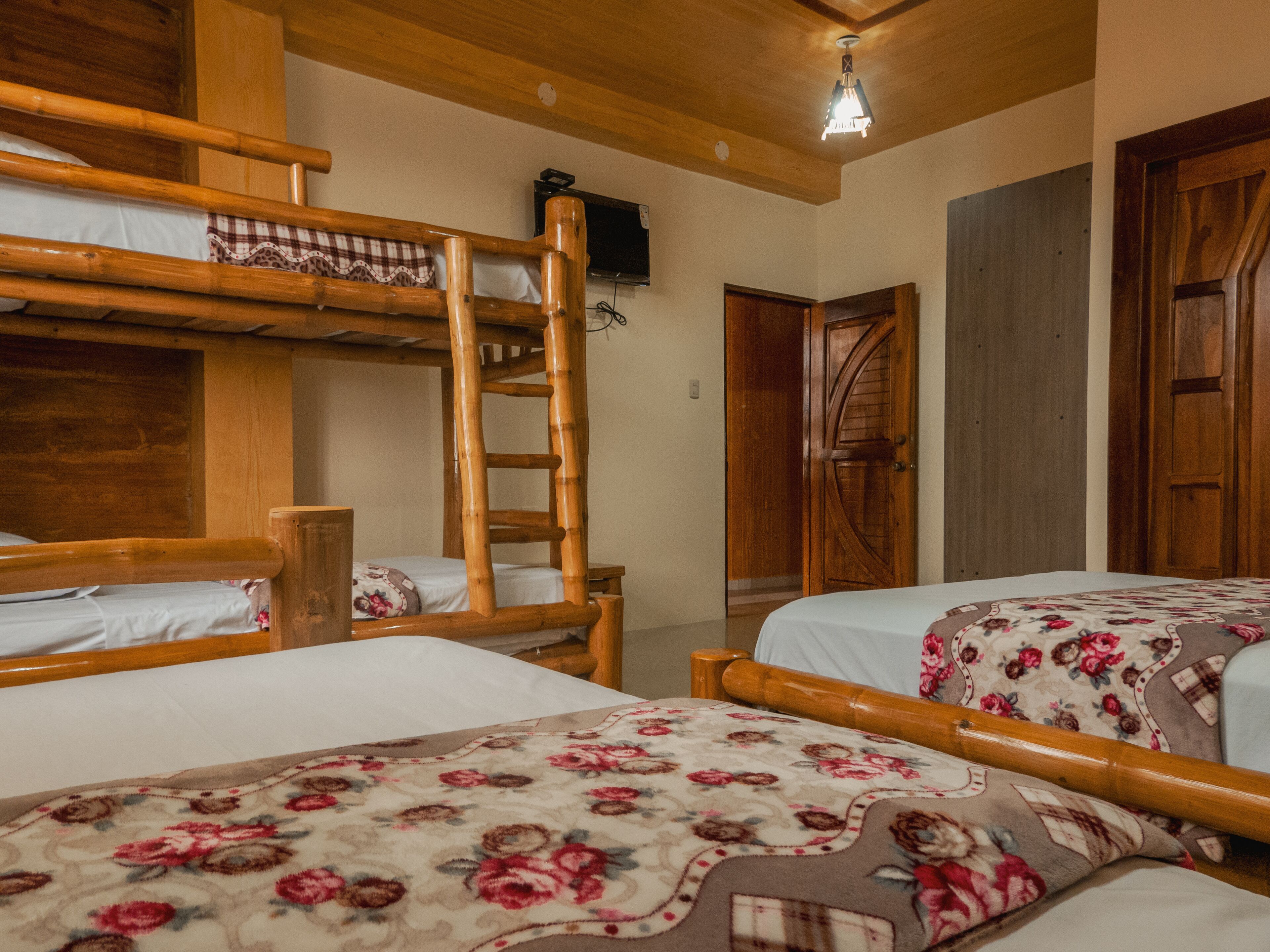 Una habitación con dos literas, muebles de madera, un televisor y una puerta.