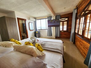 A hotel room with two beds, a television, a wardrobe, and a window with curtains. - Hostal Poseidon (Puerto Cayo)