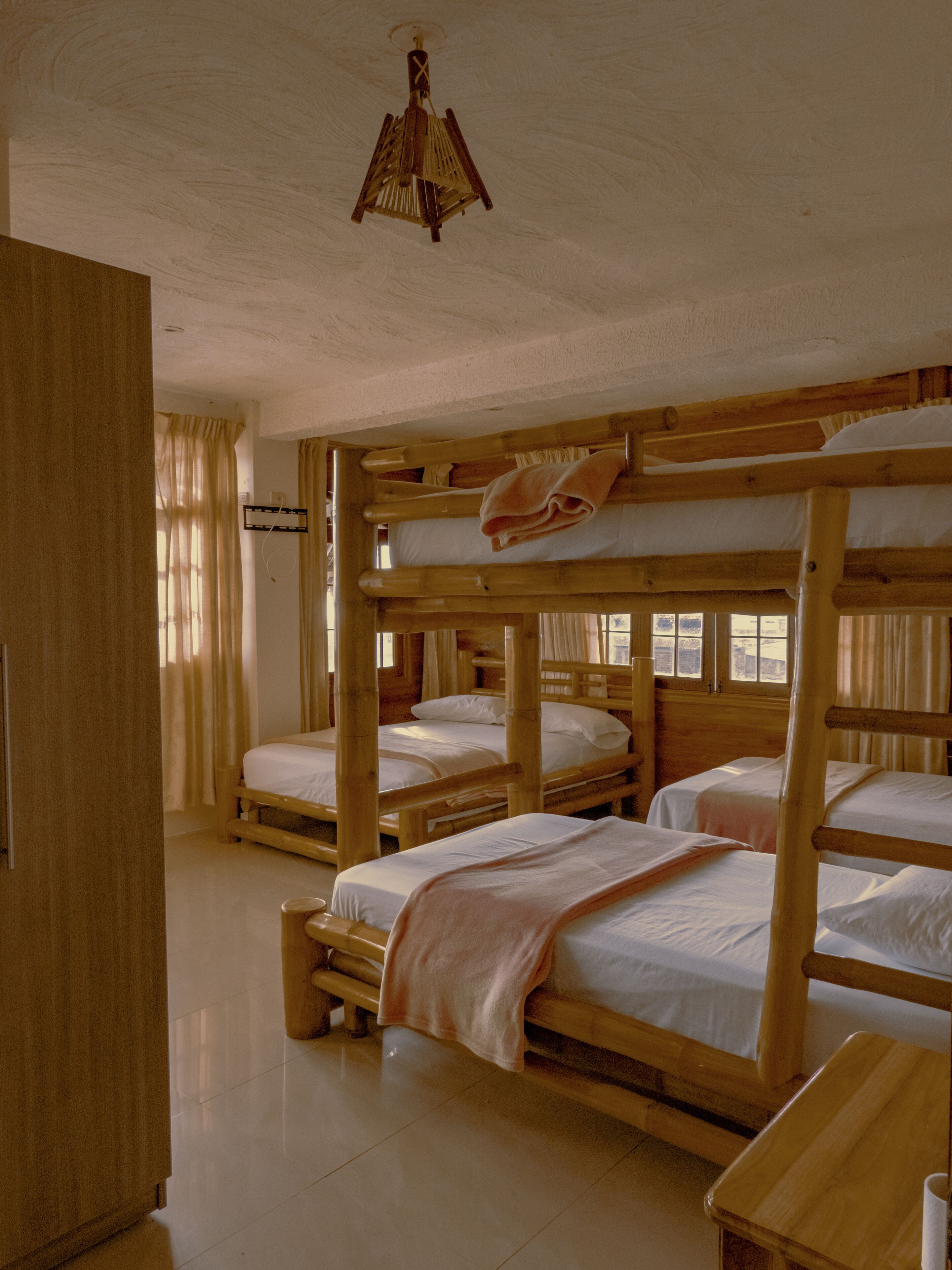 Une chambre avec des lits superposés, une armoire en bois et un ventilateur de plafond.