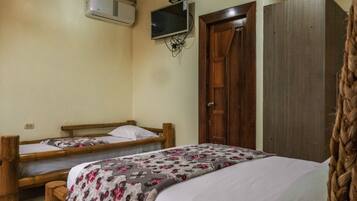 Un dormitorio con dos camas de madera, un armario de madera, un televisor montado en la pared y un equipo de aire acondicionado.