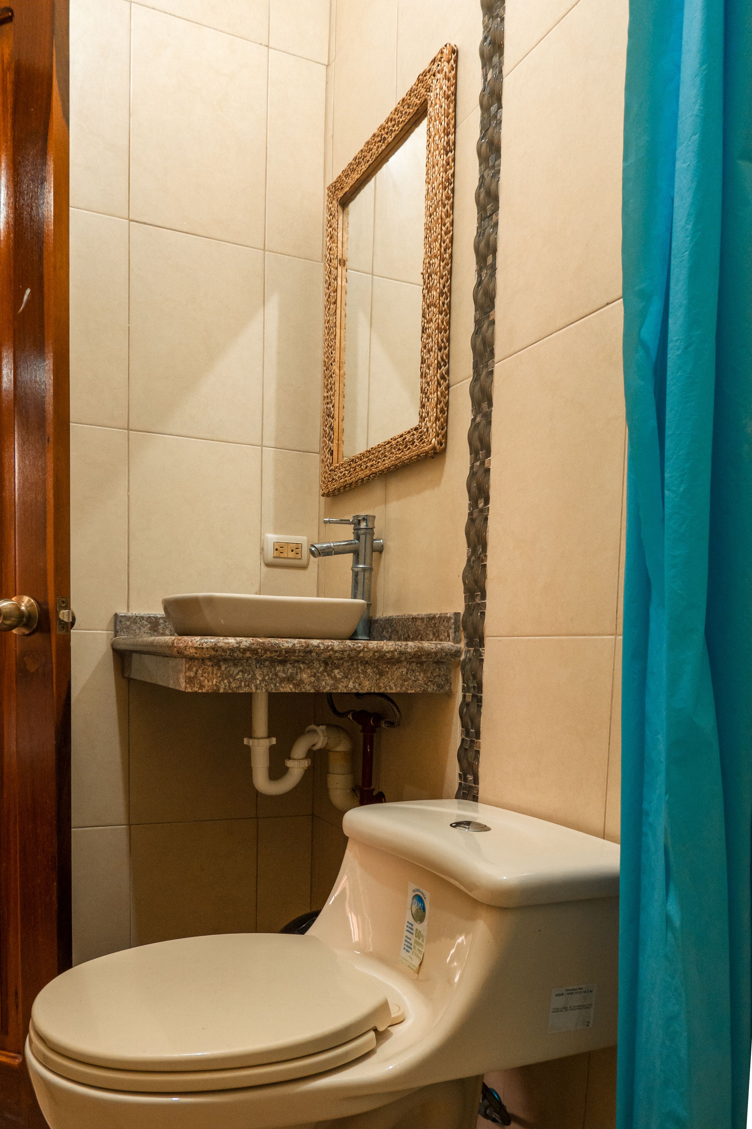 A bathroom with a toilet, sink, and mirror.