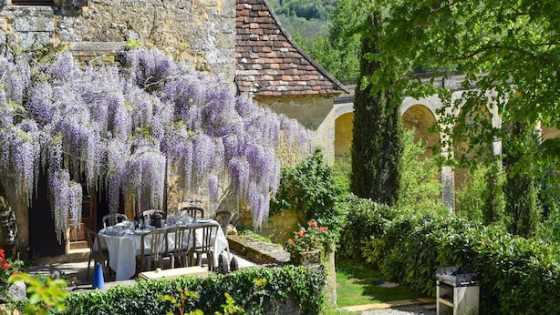 A stone building with a dining area set up outside, featuring a table and chairs. - Chateau Rochette - Four Bedroom Castle, Sleeps 8 (Mauzens-et-Miremont)