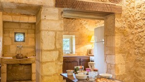 A rustic kitchen with stone walls, a wooden table with bowls, a cutting board, and a loaf of bread. - Chateau Rochette - Four Bedroom Castle, Sleeps 8 (Mauzens-et-Miremont)