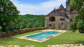 A stone-walled swimming pool with a clear blue pool, surrounded by a well-manicured lawn and a stone wall. - Chateau Rochette - Four Bedroom Castle, Sleeps 8 (Mauzens-et-Miremont)