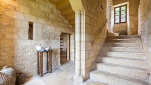 A stone-walled interior with a staircase leading to an upper level, a small window, and a table with pottery. - Chateau Rochette - Four Bedroom Castle, Sleeps 8 (Mauzens-et-Miremont)