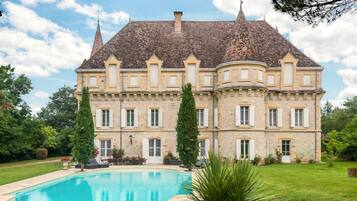 A large, historic building with a swimming pool in front.