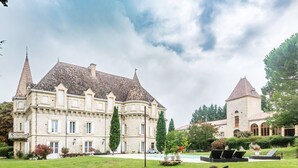 A large, historic building with a symmetrical facade, multiple towers, and a well-maintained garden with seating areas. - Chateau Quercy - Seven Bedroom Castle, Sleeps 15 (Castelsagrat)