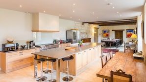 A spacious kitchen with a central island, bar stools, and a dining area with a long table and chairs. - Chateau Quercy - Seven Bedroom Castle, Sleeps 15 (Castelsagrat)