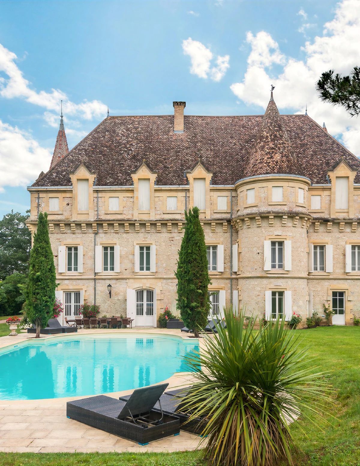 Un grand bâtiment doté d’une piscine, de deux arbres imposants et d’une pelouse bien entretenue.