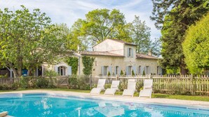 A pool with lounge chairs, a stone building with a tiled roof, and a wooden fence. - Villa Du Fleuve - Four Bedroom Villa, Sleeps 8 (Flaujagues)