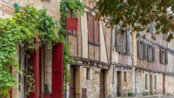 A row of traditional stone buildings with wooden shutters and a cobblestone street.