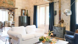 A spacious living room with exposed wooden beams, a white sofa, a blue armchair, and a coffee table with flowers. - Villa Du Fleuve - Four Bedroom Villa, Sleeps 8 (Flaujagues)