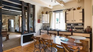 Una cocina acogedora con suelo de madera, una isla central con sillas y una ventana con cortinas.