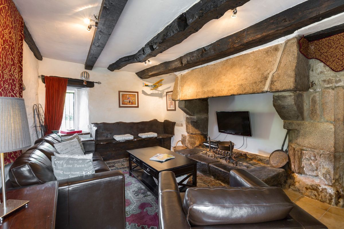 A cozy living room with a stone fireplace, leather sofas, and a flat-screen TV mounted on the wall.