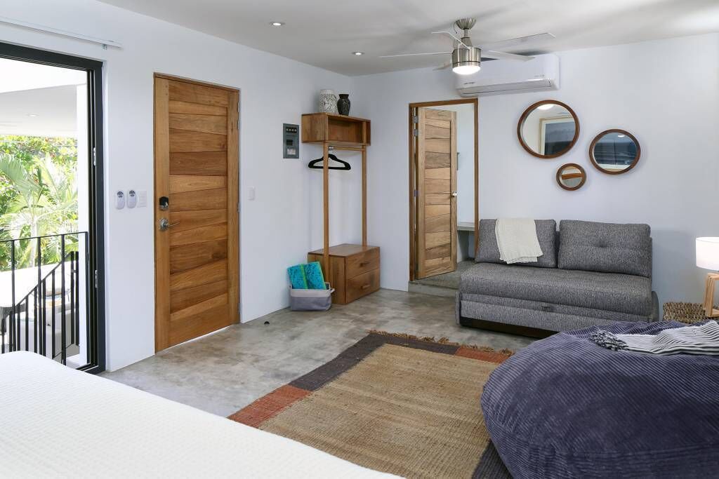 Une chambre moderne avec un canapé gris, une armoire en bois et une petite table de chevet.