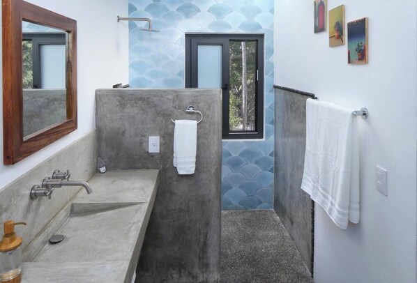 A bathroom with a large sink, a mirror, a towel rack, and a window with a view of trees.