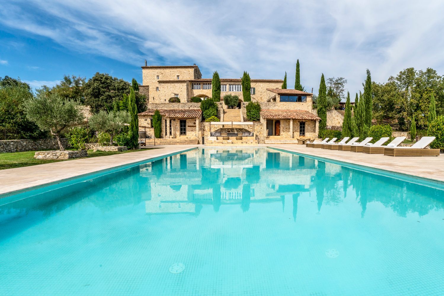 A large stone building with a swimming pool in front.