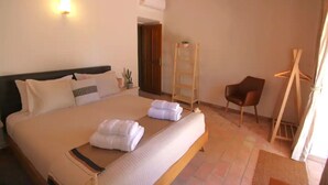 Un dormitorio con una cama grande, una escalera de madera, una silla y un aire acondicionado instalado en la pared.