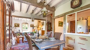 A dining area with a wooden table set for four, surrounded by wicker chairs. A patterned rug covers the floor, and a wooden cabinet is visible in the background. - Les Cypres - Three Bedroom Villa, Sleeps 6 (Vézac)