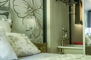 Une chambre à coucher comprenant un lit, une table de chevet, un miroir et une salle de bain avec un lavabo et une douche.