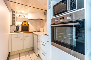Une cuisine avec des meubles blancs, un four encastré et un four à micro-ondes.
