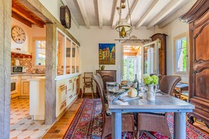 Un coin repas avec une table dressée pour deux personnes, un lustre et une vue sur la cuisine.
