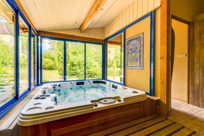 Uma banheira de hidromassagem com vista para um jardim através de grandes janelas.