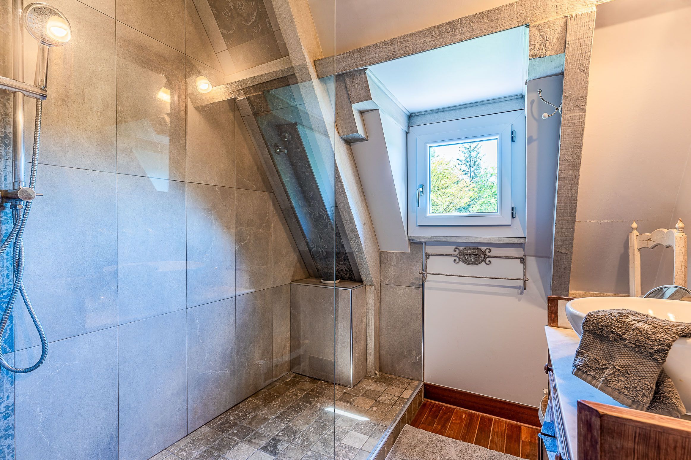 Ein Badezimmer mit Dusche, Fenster und Waschbecken.