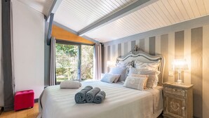 A bedroom with a large bed, a nightstand, a lamp, and a window with a view of greenery. - Les Cypres - Three Bedroom Villa, Sleeps 6 (Vézac)
