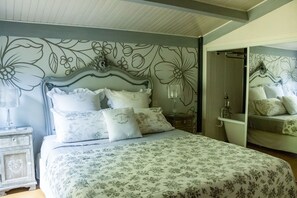 Une chambre à coucher avec un lit, une table de chevet, un miroir et une salle de bain avec une baignoire.