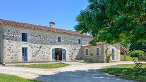 A stone building with a tiled roof, a gravel driveway, and a grassy area with a bench. - Villa Juno - Four Bedroom Villa, Sleeps 8 (Moncrabeau)