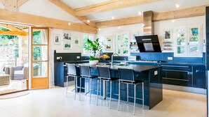 Una cocina moderna con una isla central, taburetes de bar y vistas al jardín a través de la puerta de cristal.