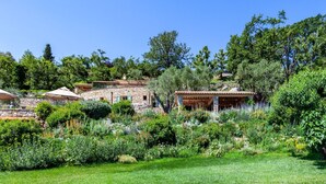 Una villa de piedra con jardín, mobiliario exterior y vistas del paisaje circundante.