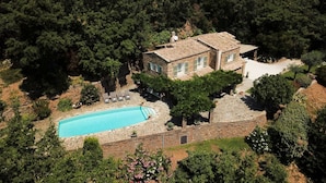 Una villa con piscina circondata da vegetazione rigogliosa e un vialetto in pietra.