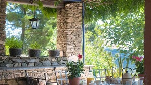 Patio esterno con pareti in pietra, sedie in metallo, un tavolo e piante in vaso.