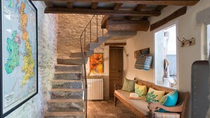 Un intérieur rustique avec un escalier en pierre, un banc en bois agrémenté de coussins et une carte accrochée au mur.