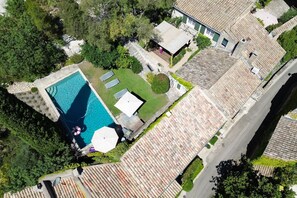 Vue aérienne d’une propriété dotée d’une piscine, d’un patio agrémenté de parasols et d’un jardin.
