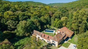 An aerial view of a property with a swimming pool, a large house, and surrounding forested hills. - Le Vieux Moulin - Seven Bedroom Villa, Sleeps 14 (Saint-Avit-Sénieur)