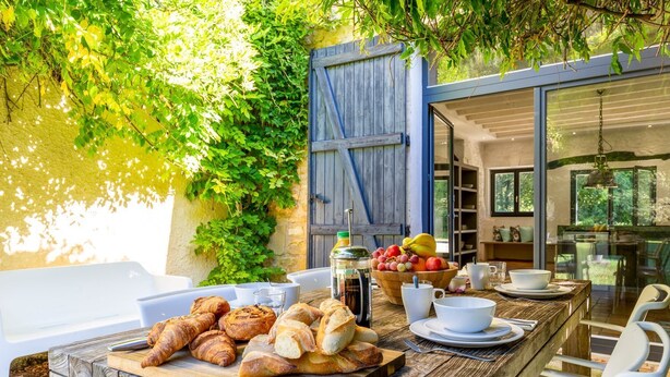 An outdoor dining area with a rustic wooden table, a variety of bread, fruits, and beverages. - Le Vieux Moulin - Seven Bedroom Villa, Sleeps 14 (Saint-Avit-Sénieur)