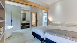 A bedroom with a large bed, a built-in bench, a white bathtub, and a walk-in closet. - Le Vieux Moulin - Seven Bedroom Villa, Sleeps 14 (Saint-Avit-Sénieur)