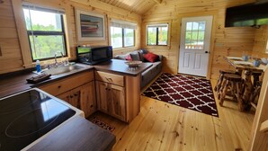 Ein Holzblockhaus-Interieur mit Küche, Essbereich und einem großen Fenster.