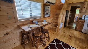Ein Holzblockbau-Innenraum mit Essbereich, Küche und einer Treppe.