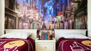 Een slaapkamer met twee bedden, een nachtkastje en een muurschildering van een straatbeeld.