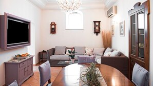A living room with a TV, sofa, dining table, and decorative items.