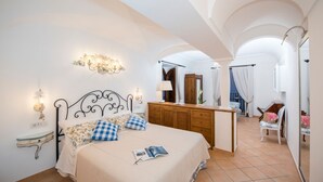 A bedroom with a bed, bedside table, lamp, and a view of the bathroom.