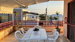 Eine Terrasse mit Tisch und Stühlen, Blumentöpfen und Blick auf die Stadtlandschaft.